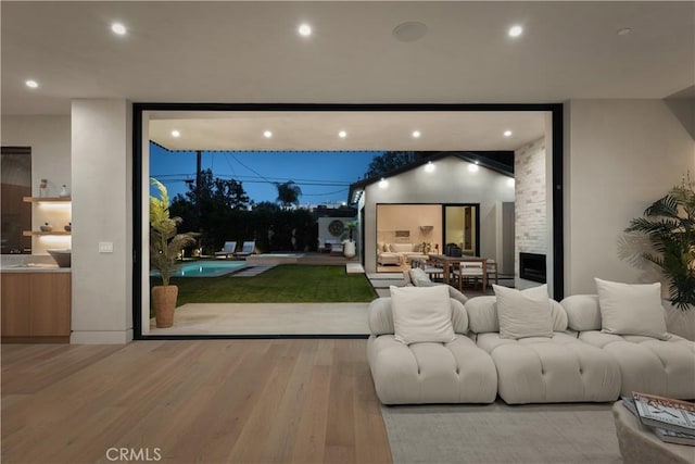 cinema room featuring a large fireplace, light wood-type flooring, and golf simulator