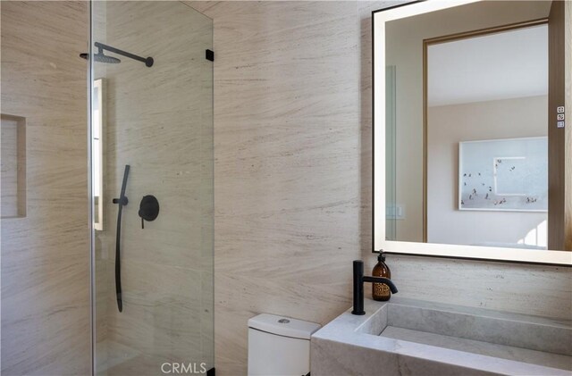 bathroom with tiled shower, sink, and toilet