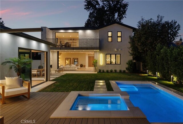 back house at dusk with an outdoor hangout area, a pool with hot tub, a balcony, a yard, and a patio area