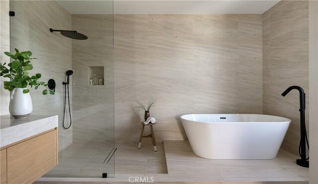 bathroom featuring tile patterned flooring, vanity, separate shower and tub, and tile walls