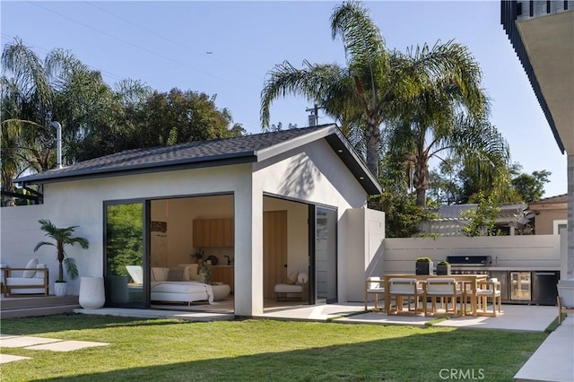 rear view of property featuring a yard, an outdoor kitchen, and a patio area