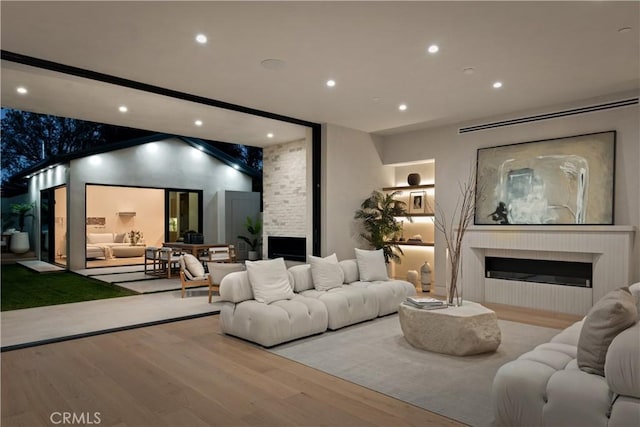 living room with a large fireplace, vaulted ceiling, and light hardwood / wood-style flooring