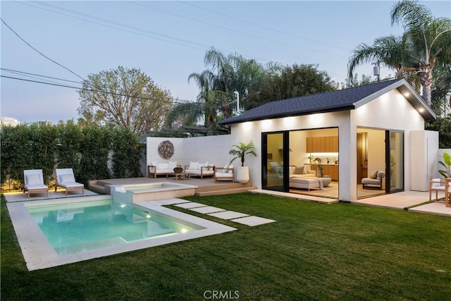 back house at dusk featuring outdoor lounge area, a yard, a patio area, and a pool side deck