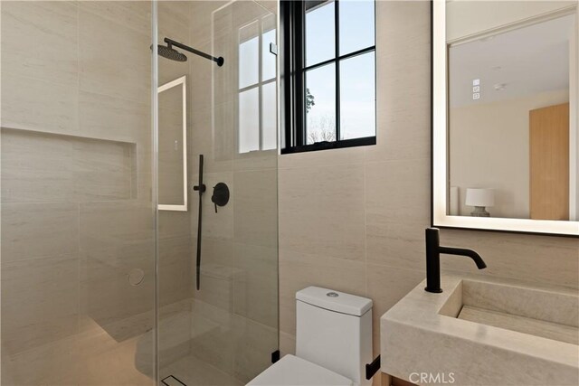 bathroom with a tile shower, sink, and toilet