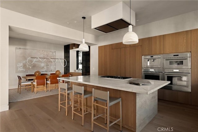 kitchen with pendant lighting, dark hardwood / wood-style flooring, light stone counters, and double oven