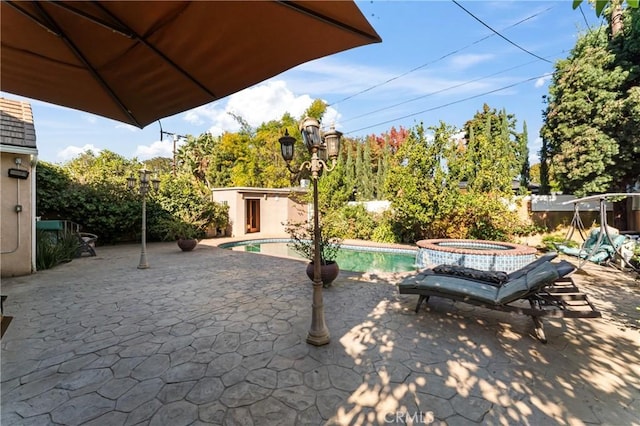 view of patio / terrace with a swimming pool with hot tub and a shed