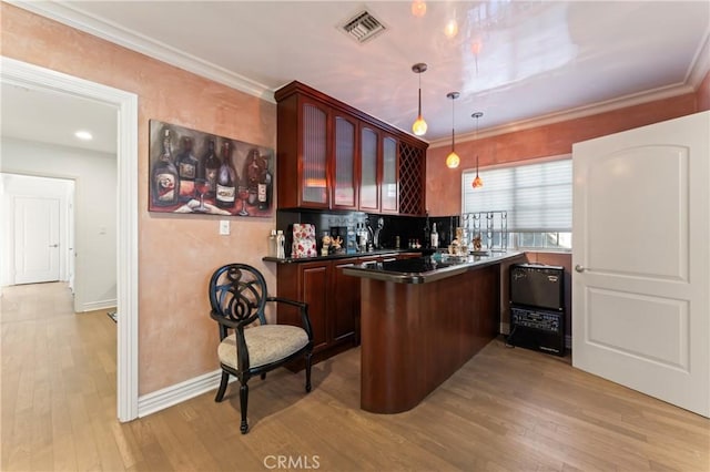 kitchen featuring kitchen peninsula, pendant lighting, light wood-type flooring, and tasteful backsplash