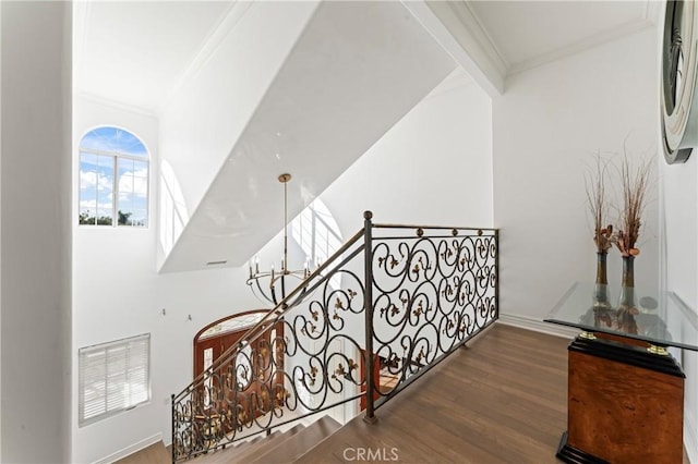 staircase featuring beam ceiling, wood-type flooring, and ornamental molding