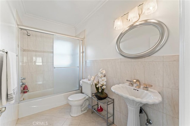 full bathroom featuring shower / bath combination with glass door, tile patterned flooring, toilet, and tile walls