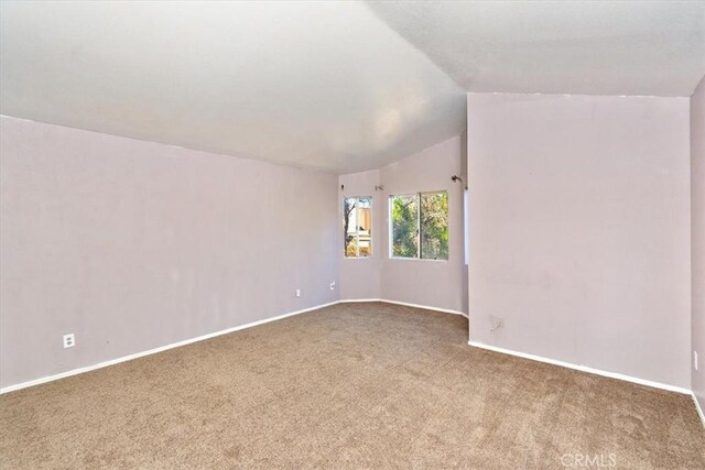 carpeted spare room with lofted ceiling