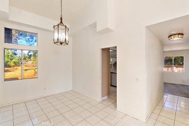 unfurnished dining area featuring light tile patterned floors and a notable chandelier