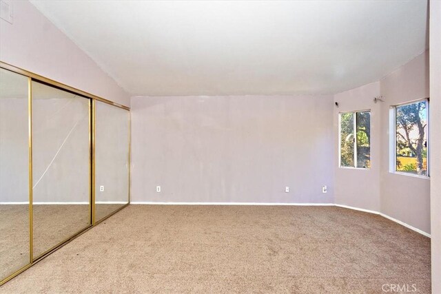 unfurnished bedroom featuring carpet flooring, a closet, and vaulted ceiling