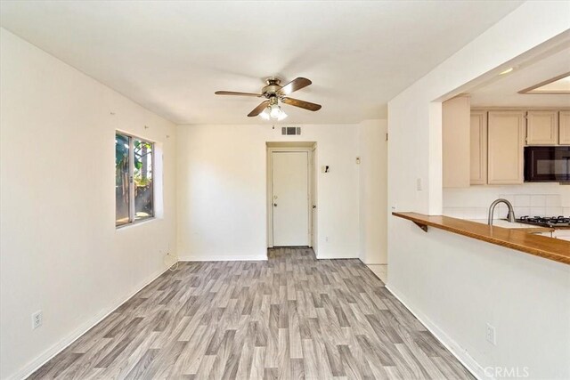 empty room featuring ceiling fan, sink, and light hardwood / wood-style flooring