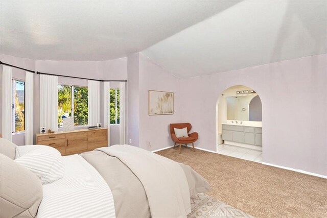 carpeted bedroom featuring connected bathroom and lofted ceiling