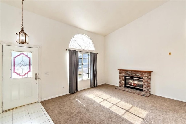 carpeted foyer entrance featuring lofted ceiling and a brick fireplace