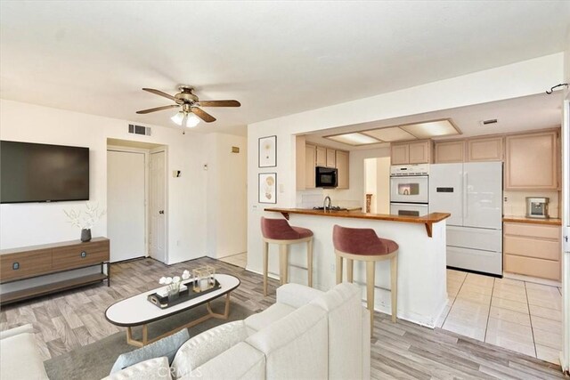 living room with ceiling fan, light hardwood / wood-style flooring, and sink