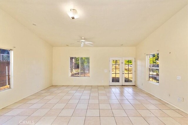 empty room with ceiling fan, light tile patterned floors, and french doors