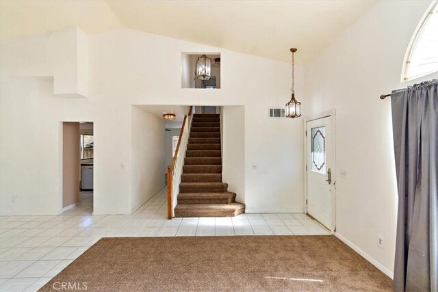 carpeted entrance foyer with high vaulted ceiling and a wealth of natural light