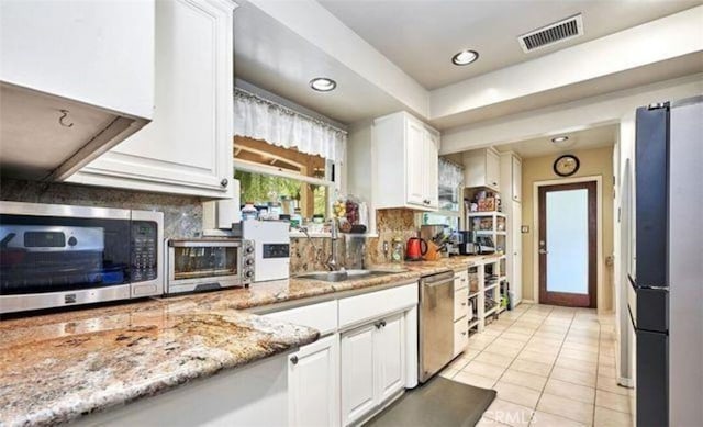 kitchen featuring white cabinetry, light stone countertops, and appliances with stainless steel finishes