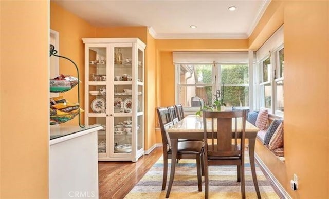 dining space with ornamental molding and light hardwood / wood-style flooring