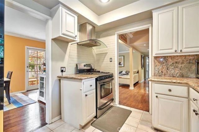 kitchen with white cabinets, stainless steel range with gas cooktop, and light hardwood / wood-style flooring