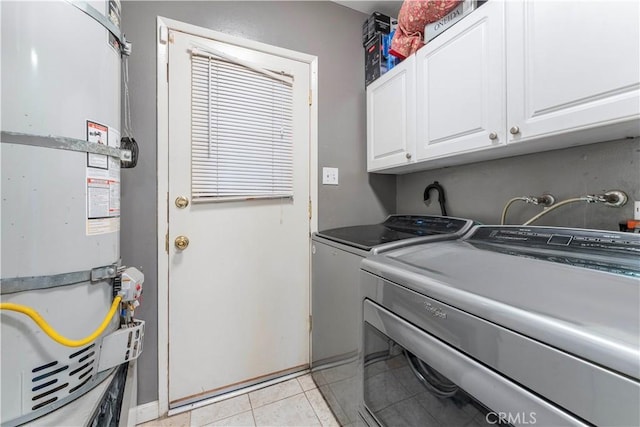 laundry area with cabinets, independent washer and dryer, strapped water heater, and light tile patterned flooring