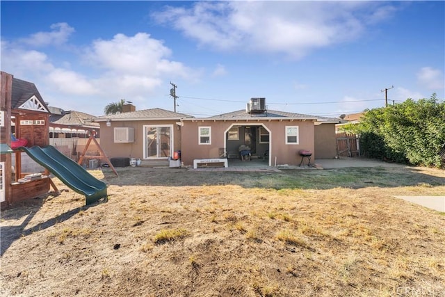 rear view of property featuring a lawn, cooling unit, a patio area, and a playground