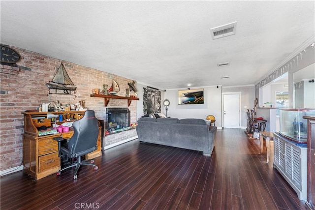 living room with dark hardwood / wood-style floors, brick wall, and a brick fireplace