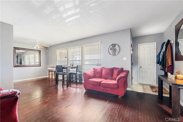 living room with a textured ceiling, ceiling fan, and dark wood-type flooring