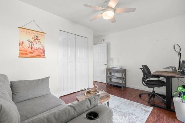 home office with dark hardwood / wood-style flooring and ceiling fan