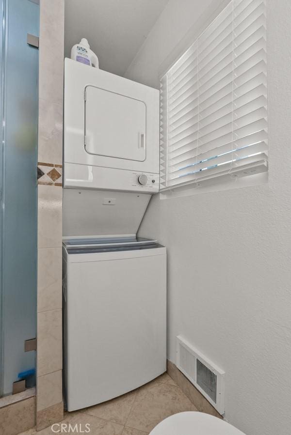 laundry room featuring light tile patterned floors and stacked washer and clothes dryer