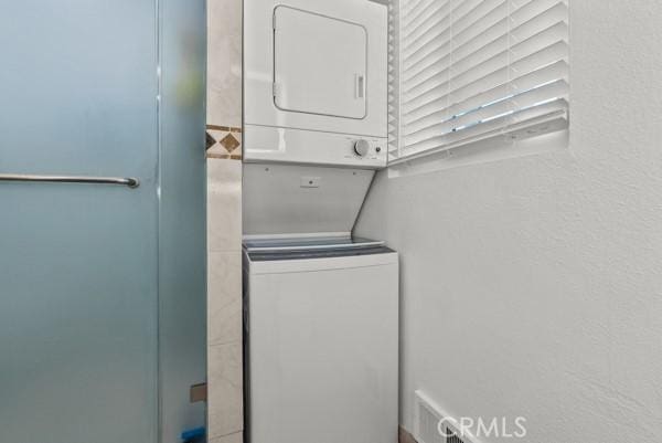 laundry room featuring stacked washer / drying machine