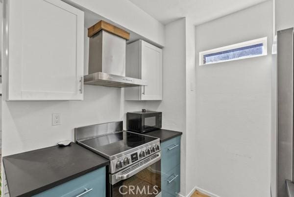 kitchen with white cabinets, electric range, and wall chimney range hood