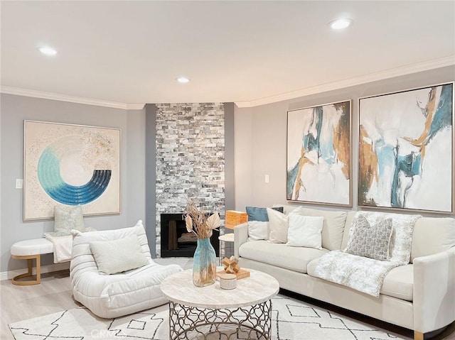 living room featuring a stone fireplace, ornamental molding, and light hardwood / wood-style floors