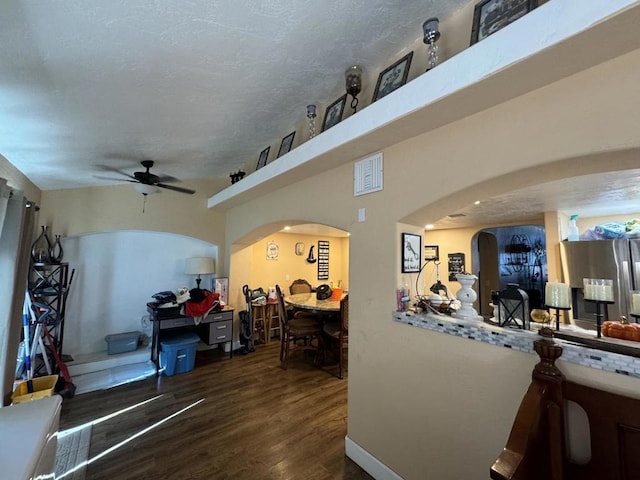 living room with ceiling fan, dark hardwood / wood-style flooring, and a textured ceiling