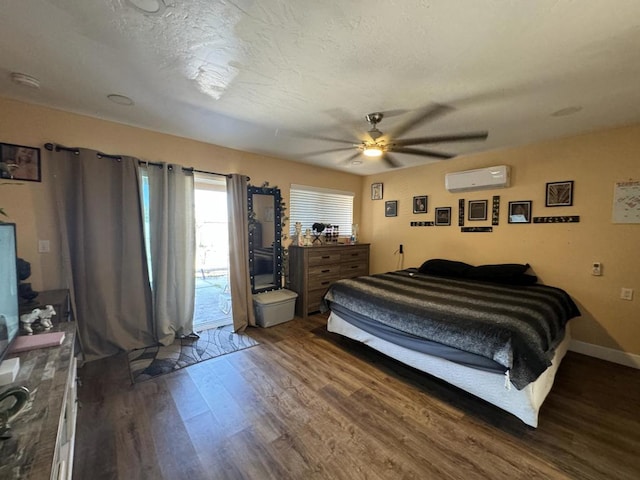 bedroom featuring access to exterior, a textured ceiling, a wall unit AC, ceiling fan, and dark wood-type flooring