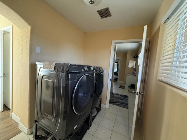 laundry room with washer and clothes dryer and light tile patterned flooring