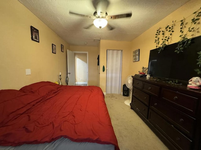 carpeted bedroom featuring ceiling fan and a textured ceiling