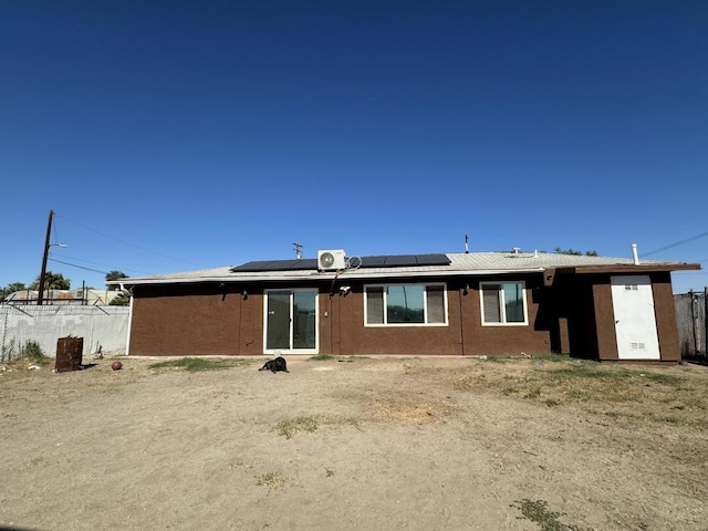 rear view of property featuring solar panels