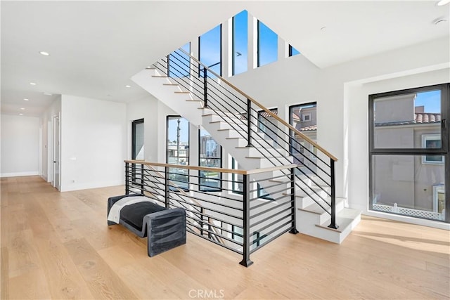 stairway with a wealth of natural light and hardwood / wood-style flooring