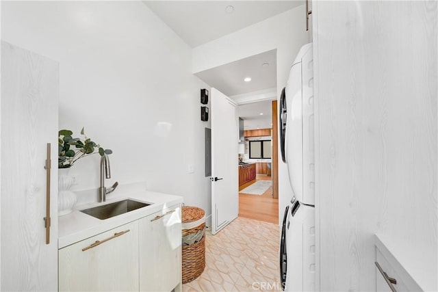 interior space featuring stacked washer and dryer, light tile patterned floors, and sink