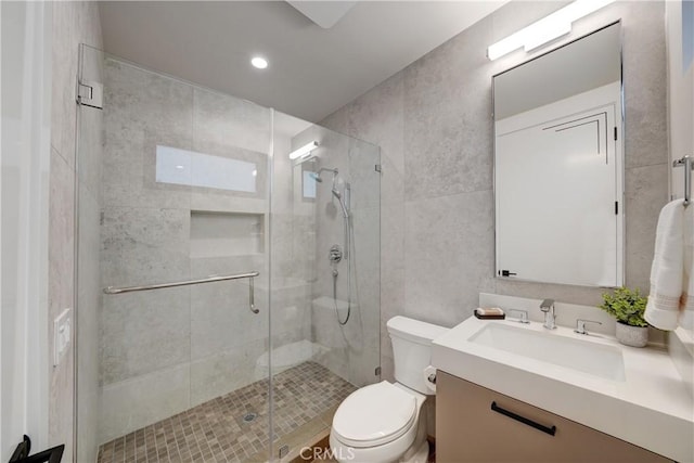 bathroom with a shower with door, toilet, and vanity