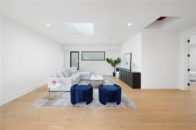 living room with a skylight and light hardwood / wood-style floors