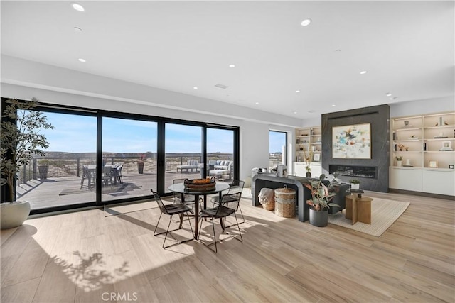 interior space featuring built in features, a large fireplace, and light hardwood / wood-style flooring