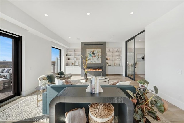 dining room featuring light wood-type flooring, a wealth of natural light, a large fireplace, and built in shelves