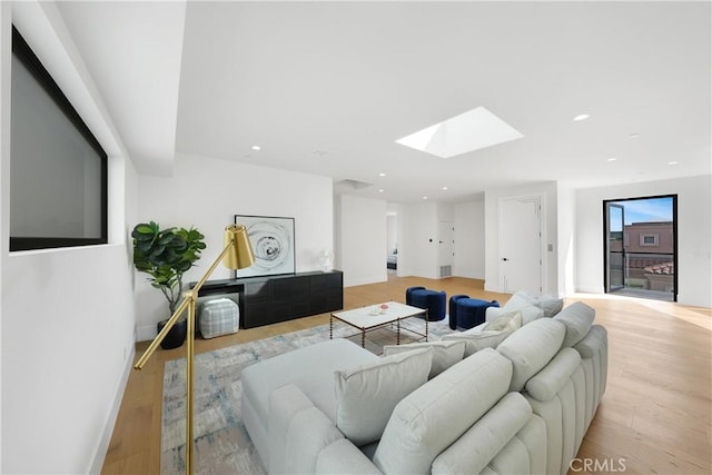 living room with a skylight and light hardwood / wood-style flooring