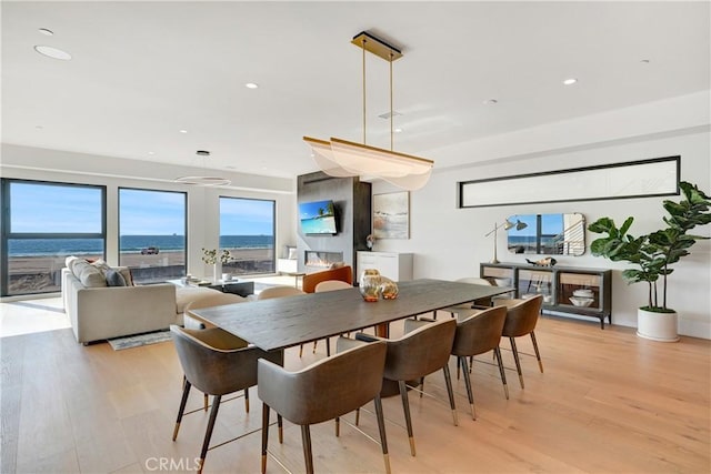 dining area featuring a water view, french doors, and light hardwood / wood-style floors