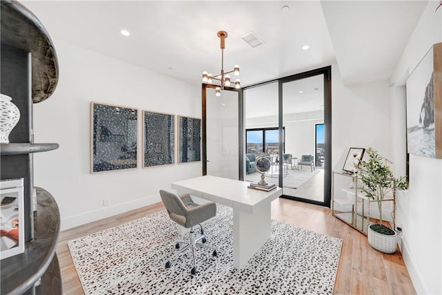 office featuring a chandelier, a wall of windows, and light hardwood / wood-style floors