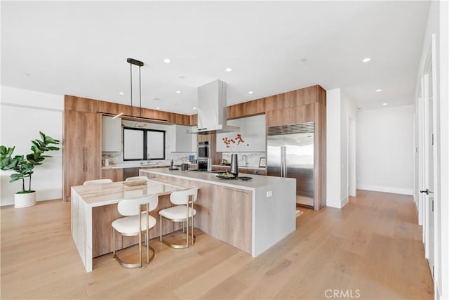 kitchen with a kitchen bar, stainless steel appliances, hanging light fixtures, a large island, and island range hood