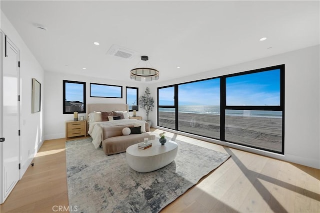 bedroom featuring access to exterior, light hardwood / wood-style floors, and a water view